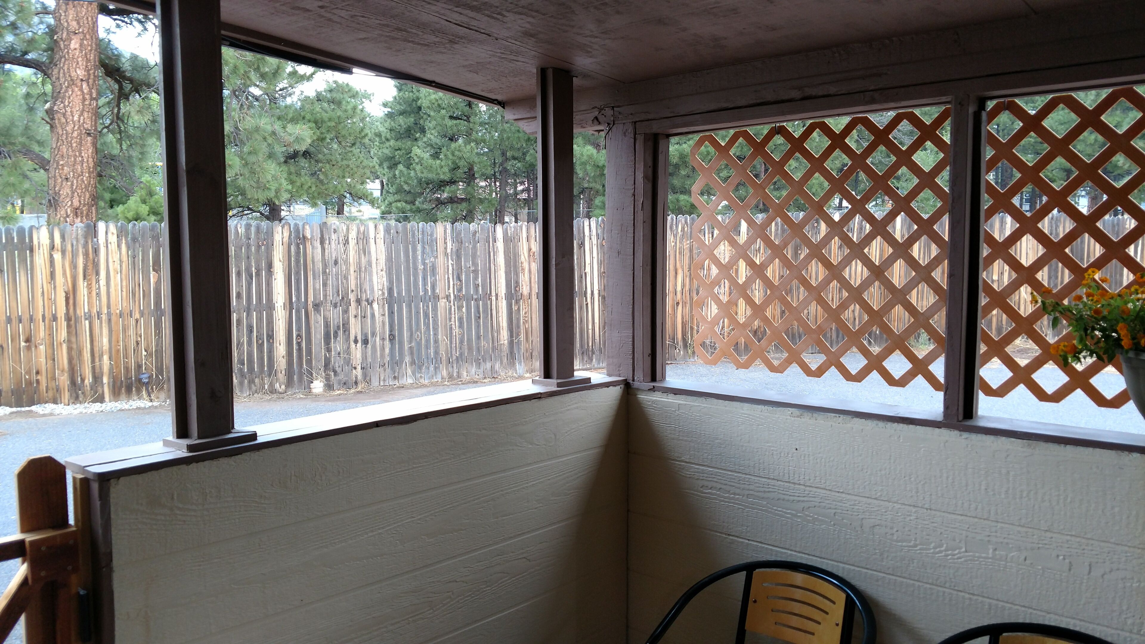 A corner of a room with a wooden partition, a window with a lattice design, and a chair.
