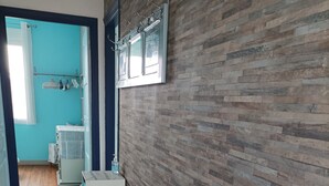 A hallway with a white bench, a tiled floor, a wooden wall, and a door leading to a bathroom. - CHARMING HOUSE - ALL COMFORTS - RATED 2 STARS (Le Crotoy)