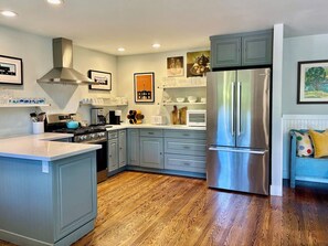 Una cocina moderna con una isla central, electrodomésticos de acero inoxidable y suelo de madera.