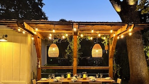 Ein Essbereich im Freien mit einer Pergola, Lichterketten und einem Tisch für sechs Personen.