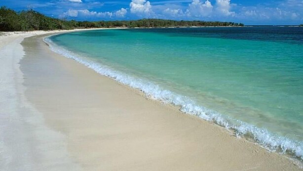A beach with clear turquoise water and a sandy shore.