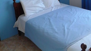 A bedroom with a bed, wooden headboard, and a painting on the wall.