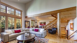 A spacious living room with a large sectional sofa, a round coffee table, and a staircase with wooden railings. - Easy Ski inOut-Private Home -NOT Condo or Townhome-in Upper DV-Silverlake (Park City)