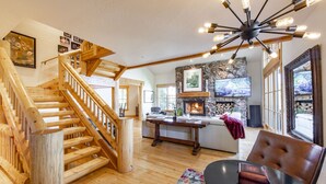 A spacious living area with a wooden staircase, a fireplace, a stone accent wall, and a large window. - Easy Ski inOut-Private Home -NOT Condo or Townhome-in Upper DV-Silverlake (Park City)