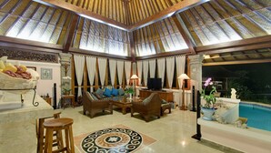 Eine großzügige Lounge mit hoher Decke, bequemen Sitzgelegenheiten, einem Poolbereich und einer Essecke.