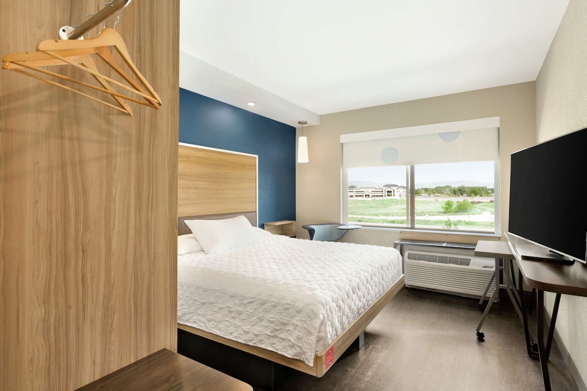 Ein Hotelzimmer mit Bett, Schreibtisch, Fernseher und Fenster mit Blick ins Freie.