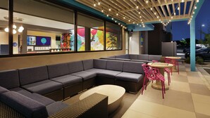 A modern outdoor seating area with a sectional sofa, round tables, and chairs.
