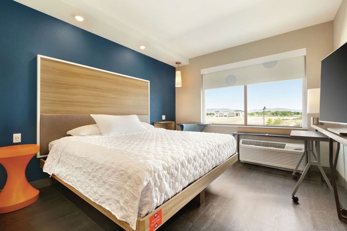 Ein modernes Hotelzimmer mit Bett, Schreibtisch, Stuhl, Heizung und einem großen Fenster mit Blick.