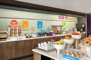 Ein Frühstücksbuffet mit verschiedenen Speisen, darunter Waffeln, Eier und Donuts.