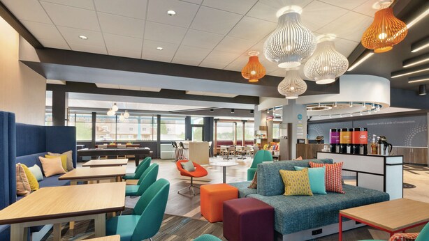 A modern lounge area with seating, tables, and a breakfast bar.