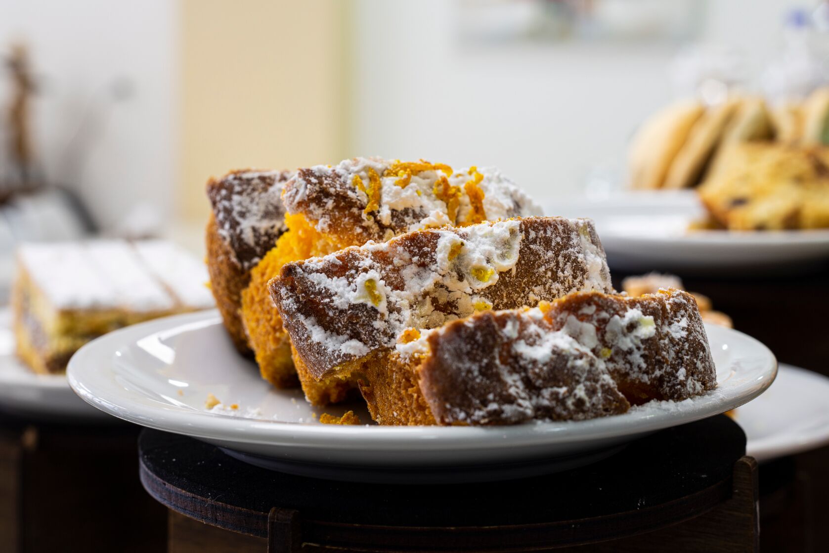 A dessert plate with slices of cake topped with powdered sugar and orange zest.