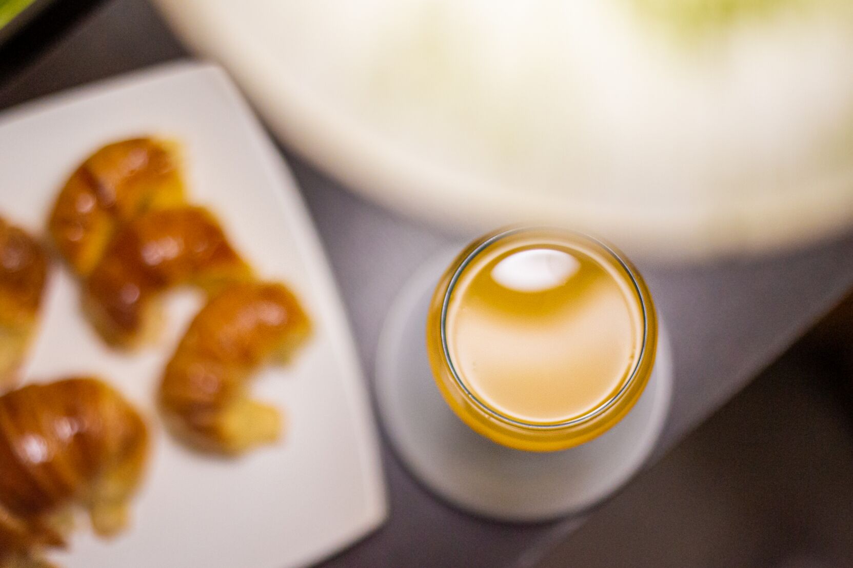 Un vaso de un líquido transparente, posiblemente una bebida, junto a un plato con cruasanes.