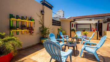 Relax in the serene outdoor patio surrounded by lush greenery and comfortable seating.