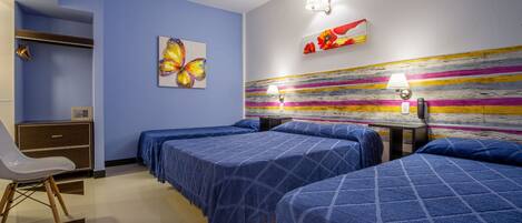 A hotel room with two beds, a desk, a chair, a ceiling fan, and artwork on the walls.
