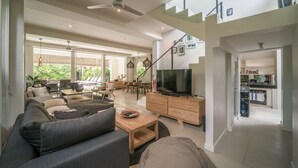 A spacious living area with a modern sofa, a television, and a dining area with a table and chairs. - Levi Villa (Seminyak)