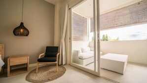 A modern living room with a sliding glass door leading to a balcony with a white sofa and a white ottoman. - Levi Villa (Seminyak)