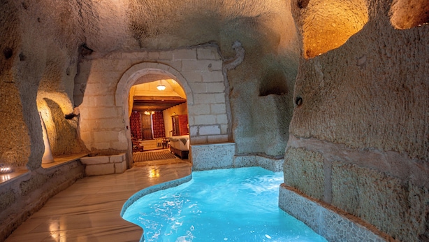 Un área de spa con pared de piedra, suelo de madera y una piscina.