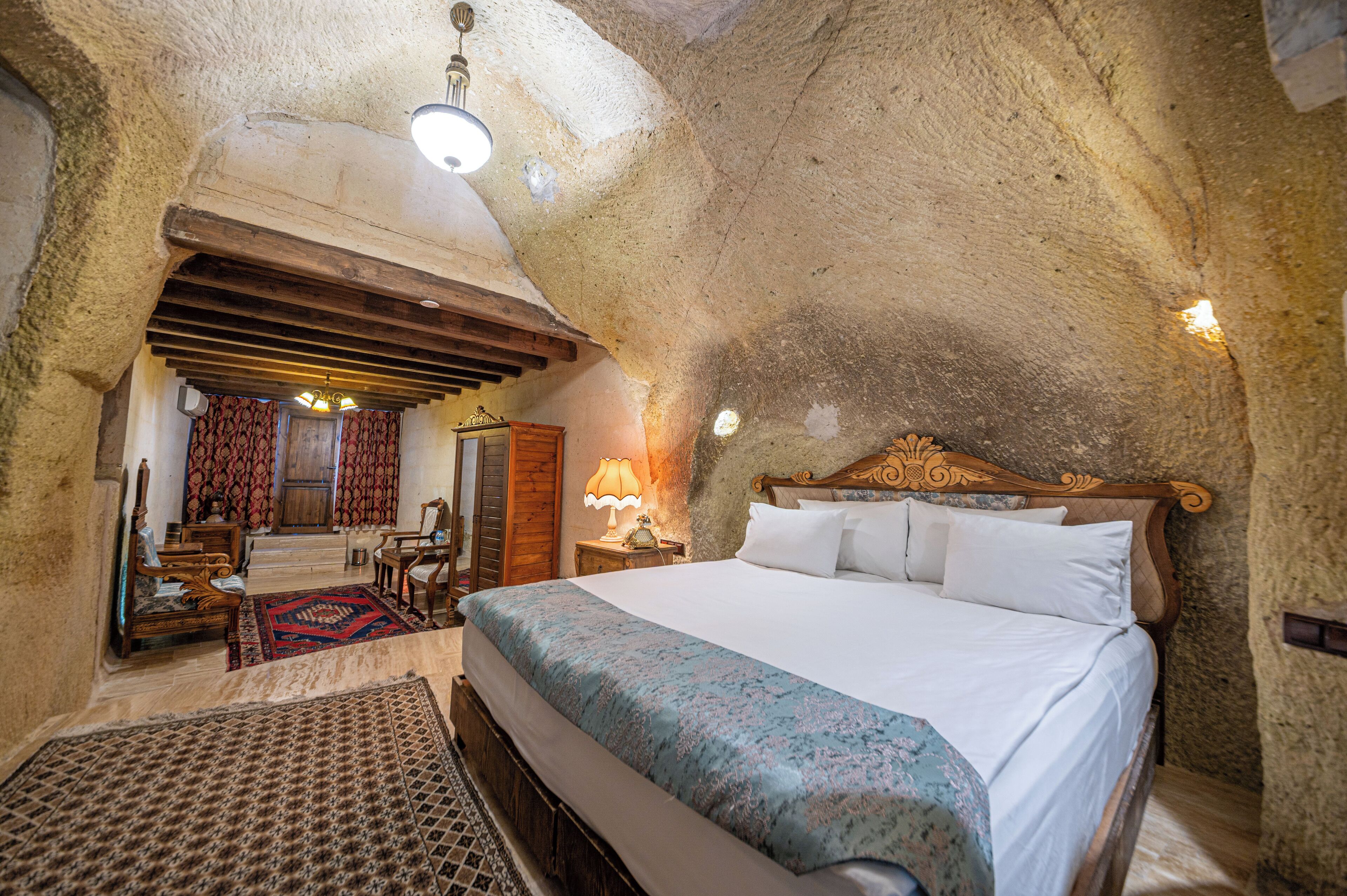 Une chambre avec un grand lit, une tête de lit en bois et un plafond en pierre.