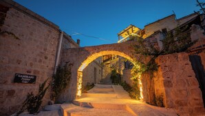 Un camino de piedra que lleva a la entrada de un edificio con un arco iluminado.