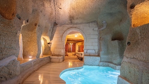 Un espacio de spa con hidromasaje, paredes de piedra y un banco de madera.