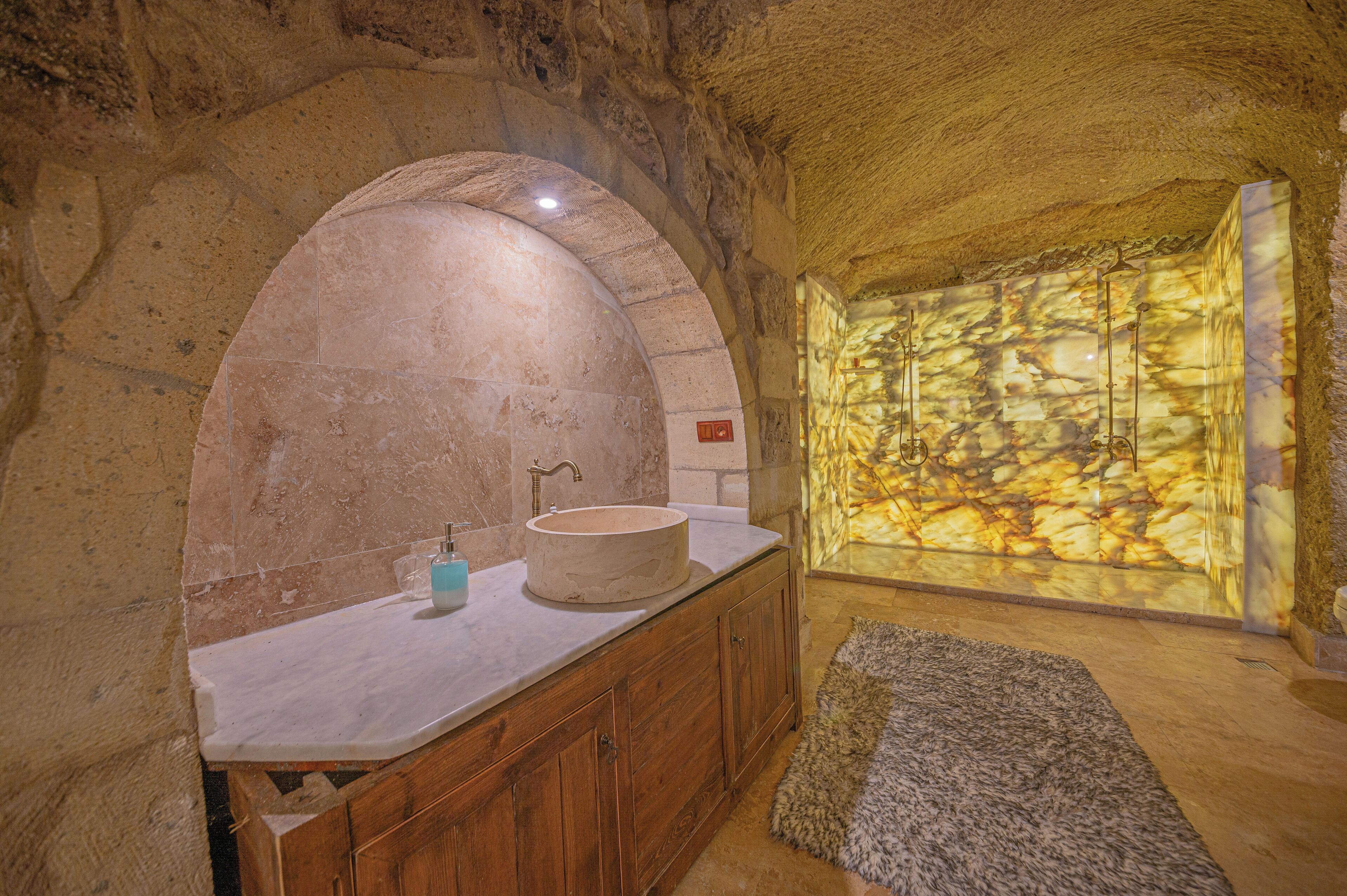 A bathroom with a stone sink, wooden cabinets, and a stone wall.