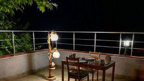 Ein Essbereich im Freien mit Tisch, Stühlen, einer Lampe und einem Geländer.