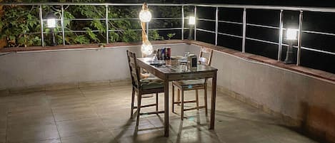 Un espace extérieur aménagé pour les repas, avec une table et des chaises, entouré d’une rambarde et d’arbres.