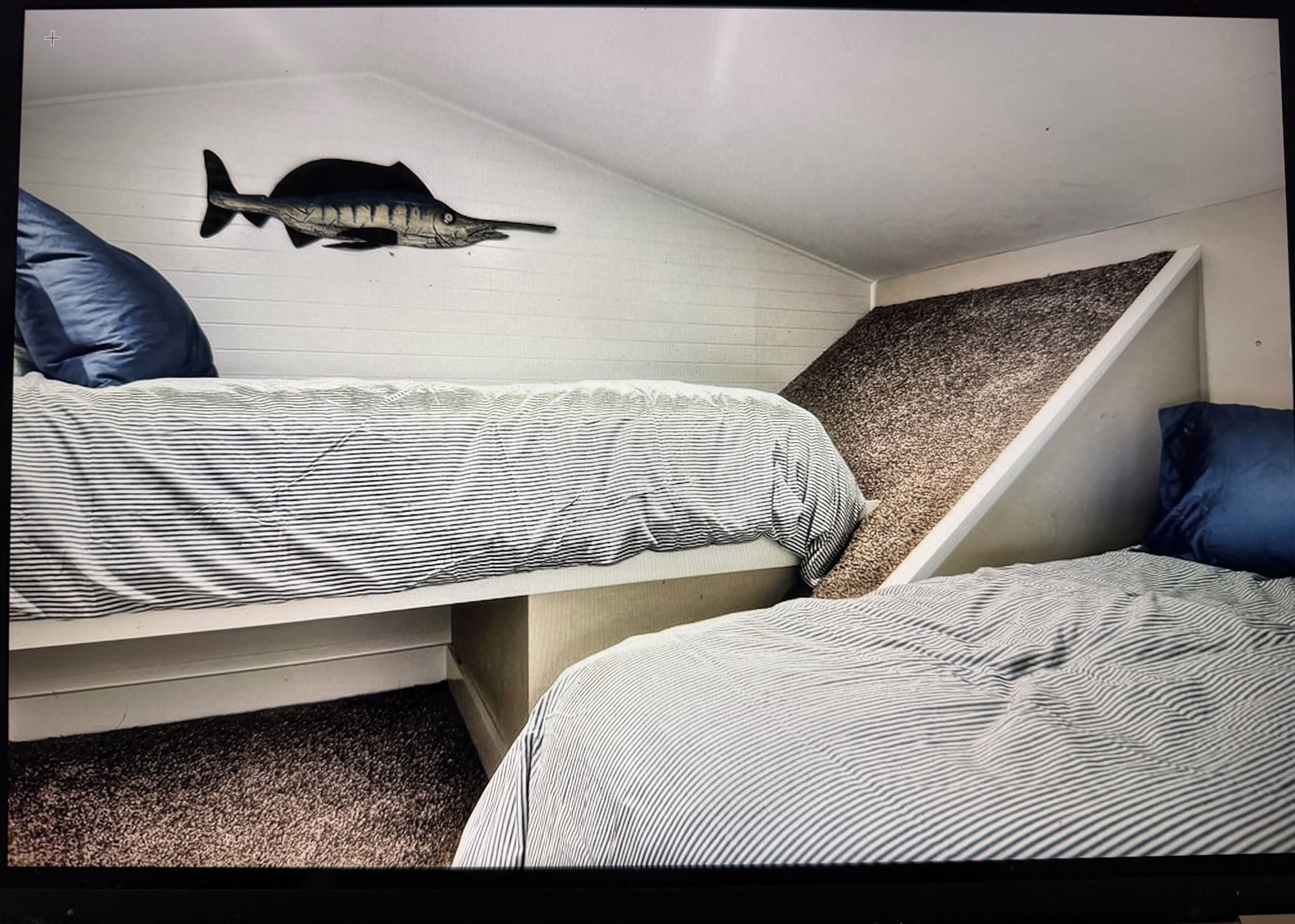Un dormitorio con dos camas, una decoración de pez en la pared y un techo inclinado.