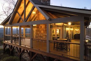 Eine Holzterrasse mit Sitzgelegenheiten im Freien, eine Steinmauer und ein überdachter Bereich mit Grill.