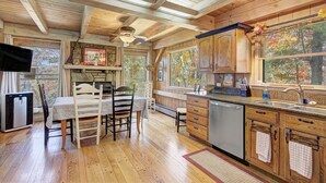 L’intérieur d’une cabane en bois comprend un coin repas, une cuisine et de grandes fenêtres.