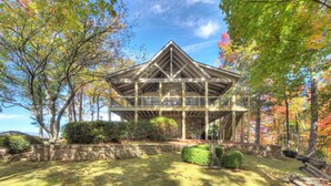 Un grand pavillon ouvert, doté de fondations en pierre et de poutres en bois, entouré d’arbres et d’une pelouse bien entretenue.