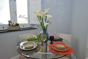Una mesa de comedor preparada con platos, vasos y un jarrón con flores.