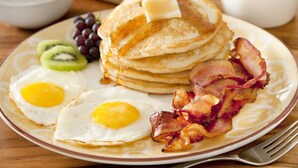 A breakfast plate with pancakes, eggs, bacon, and fruit. - The Whitestone Inn (Adentan)