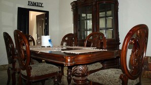 A dining room with a wooden table, six chairs, and a cabinet with glass doors. - The Whitestone Inn (Adentan)