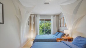 Quarto com duas camas, varanda e vista para o verde.