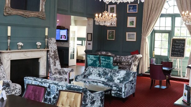 A room with a fireplace, a chandelier, a sofa, and a dining table with chairs. - Kings Newmarket (Newmarket)