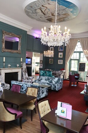 A room with a fireplace, a chandelier, a sofa, and a dining table with chairs. - Kings Newmarket (Newmarket)