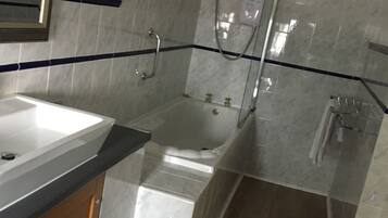 A modern bathroom with a bathtub, shower, and sink.