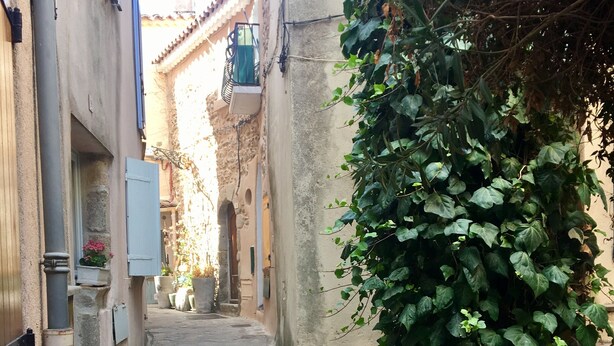 A narrow stone-paved alleyway flanked by buildings with traditional architecture, including a visible window with a shutter and a wall-mounted light fixture. - Authentic village house in the center of Ramatuelle (Ramatuelle)
