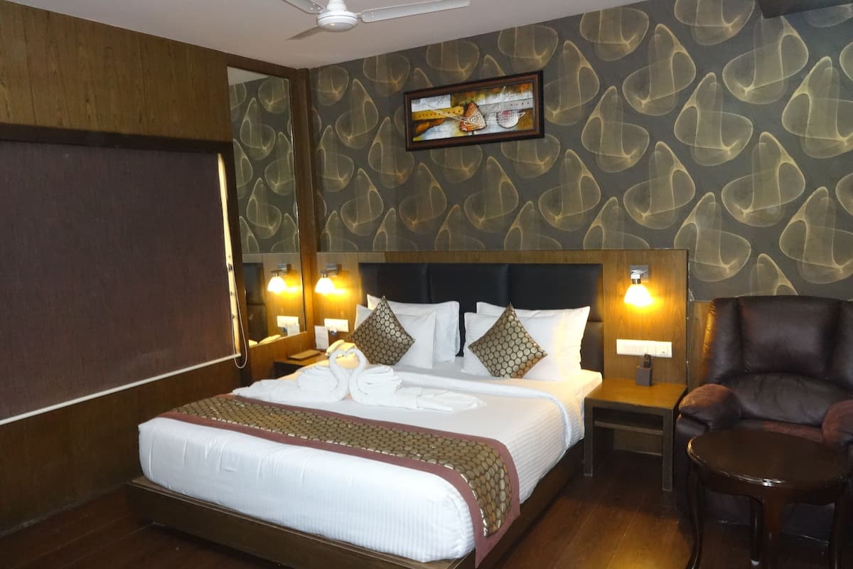 A hotel room with a large bed, two bedside tables with lamps, a chair, and a ceiling fan.