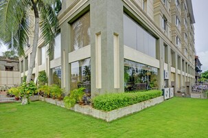 Un edificio moderno con grandes ventanales, un césped cuidado y varias plantas en macetas.