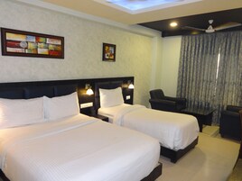 A hotel room with two beds, a desk, a chair, and a ceiling fan.