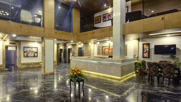 Um hall amplo com piso de mármore, balcão de recepção e área de estar.