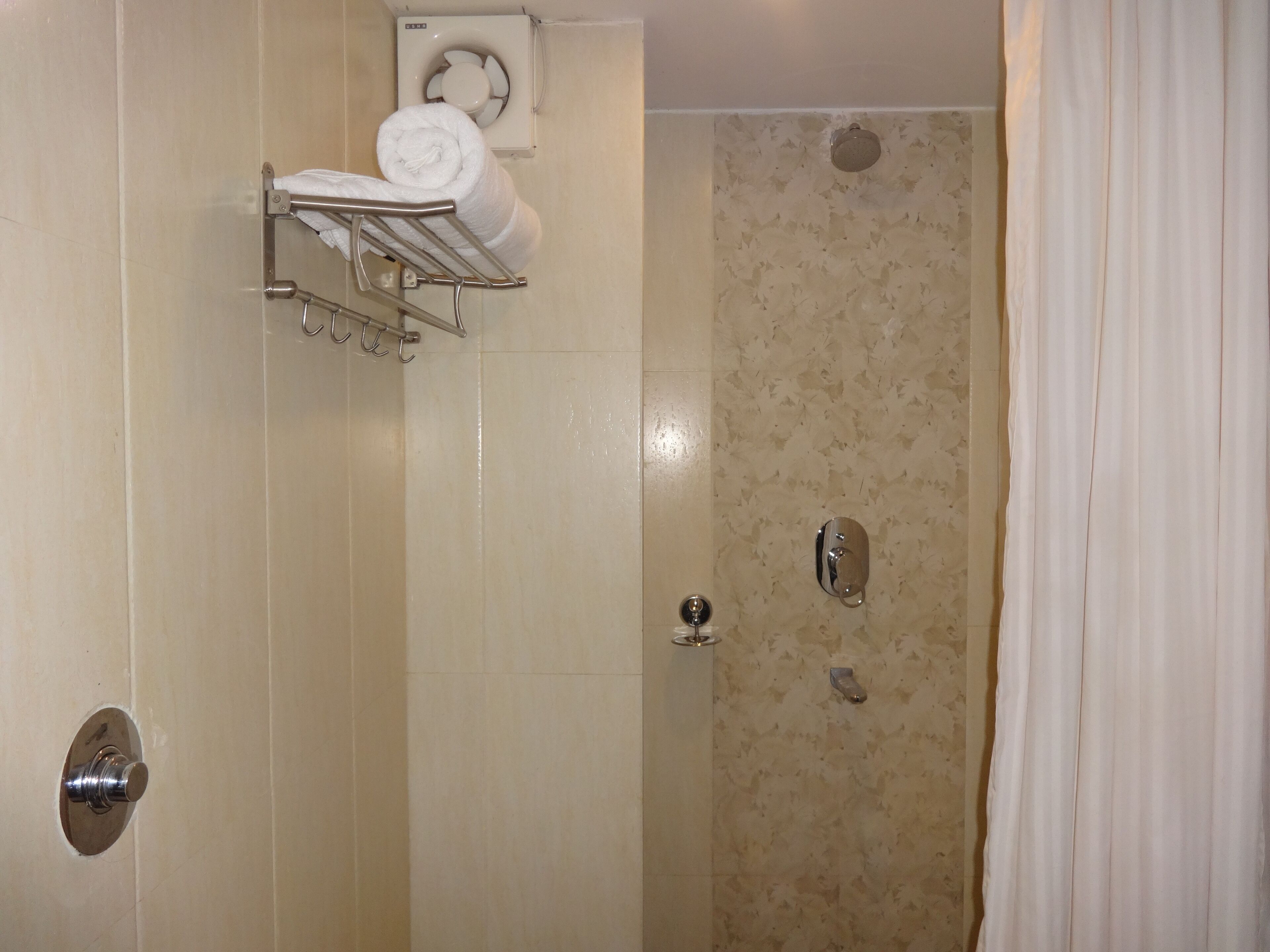A bathroom with a shower, a towel rack, and a toilet.
