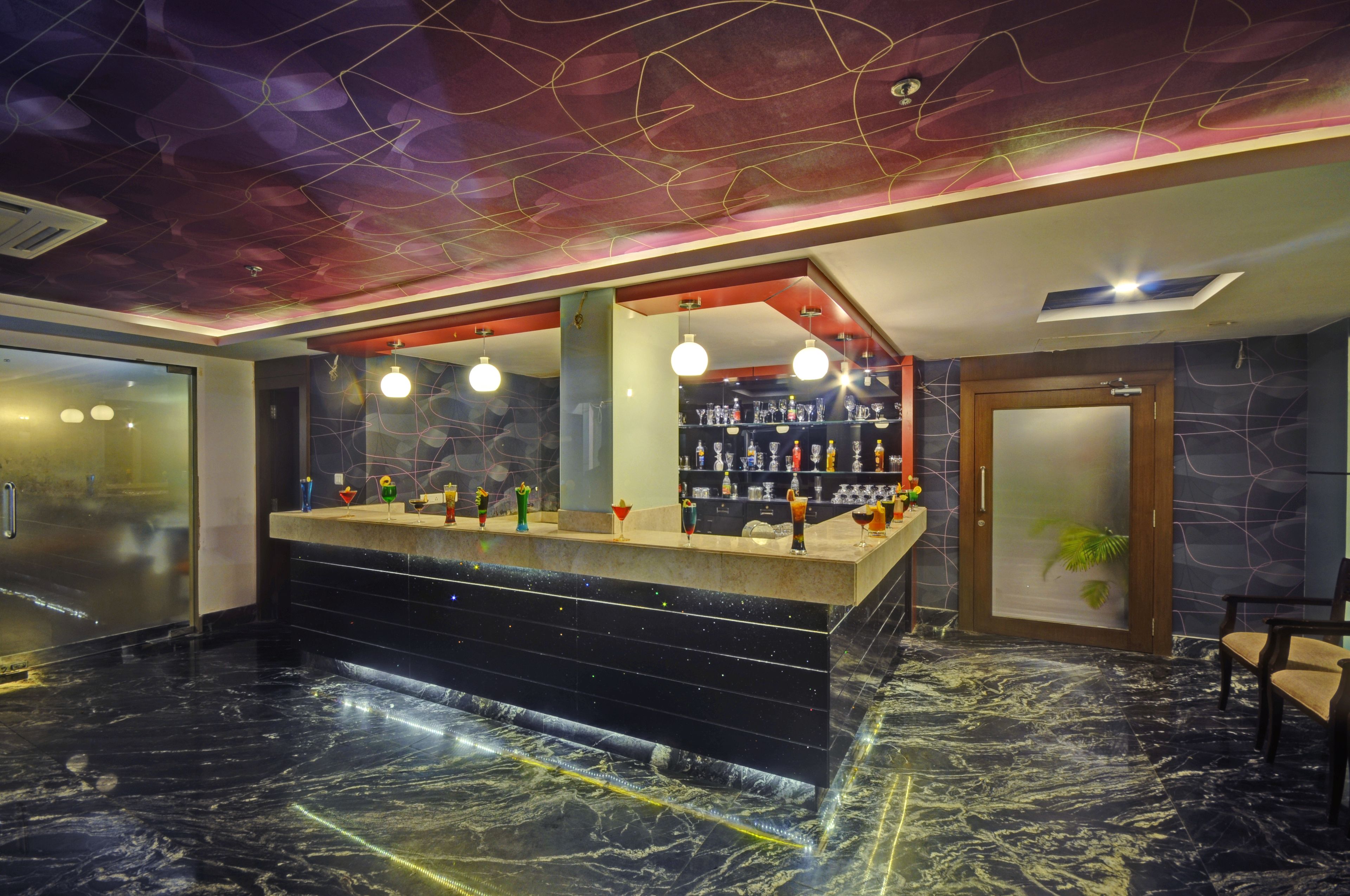 A bar area with a marble floor, a counter with various bottles, and a ceiling with a unique design.
