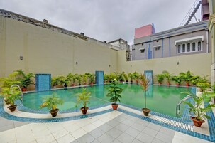 Una piscina interior con bordes de azulejos y plantas en macetas alrededor.