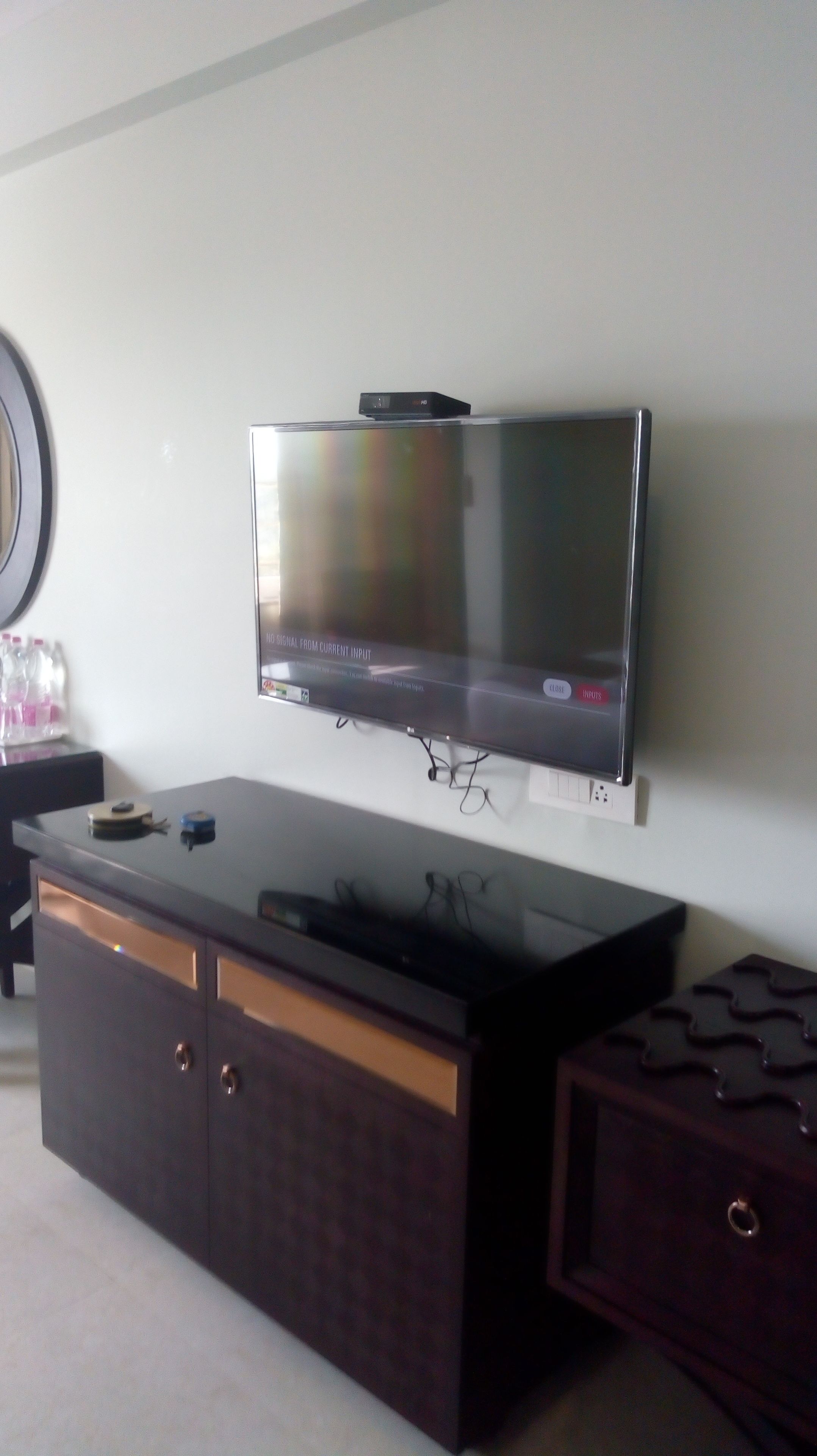 Un televisor de pantalla plana montado en la pared sobre un mueble bajo de madera oscura con cajones.