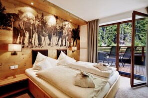 Une chambre d’hôtel avec un grand lit, une tête de lit en bois et une fresque représentant des skieurs.