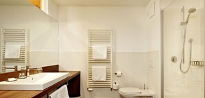 Une salle de bain moderne avec un meuble-lavabo en bois, des toilettes, une douche et un grand miroir.