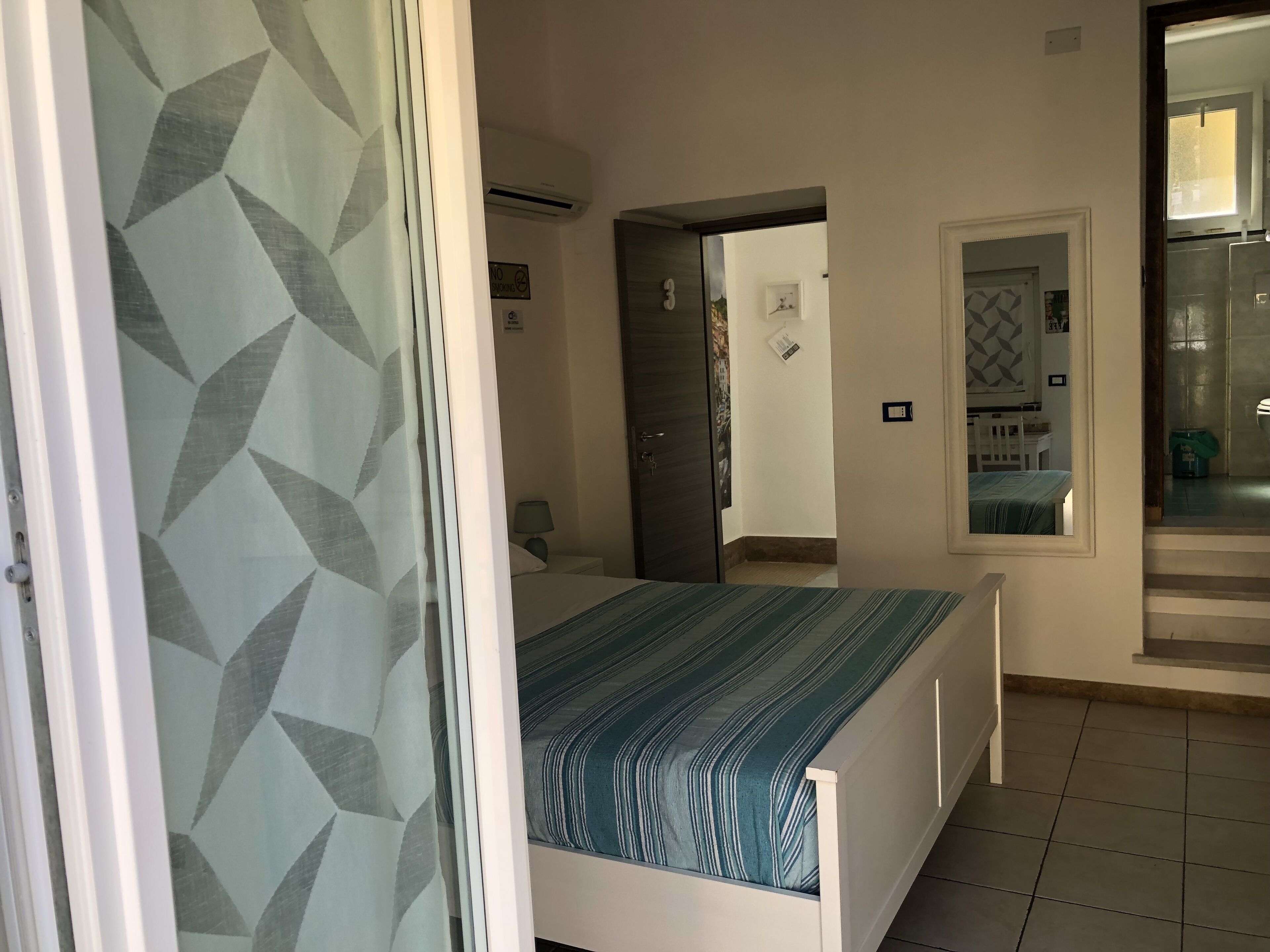 A hotel room with a bed, a bathroom, and a view of the outside.